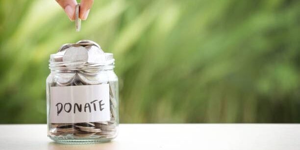 Hand putting Coins in glass jar for giving and donation concept